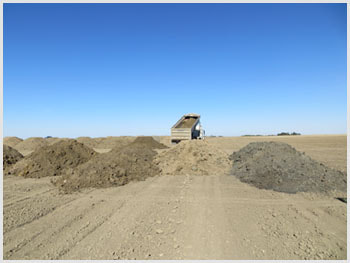 Soil stockpiles and a dump truck at the Floral Landfarm